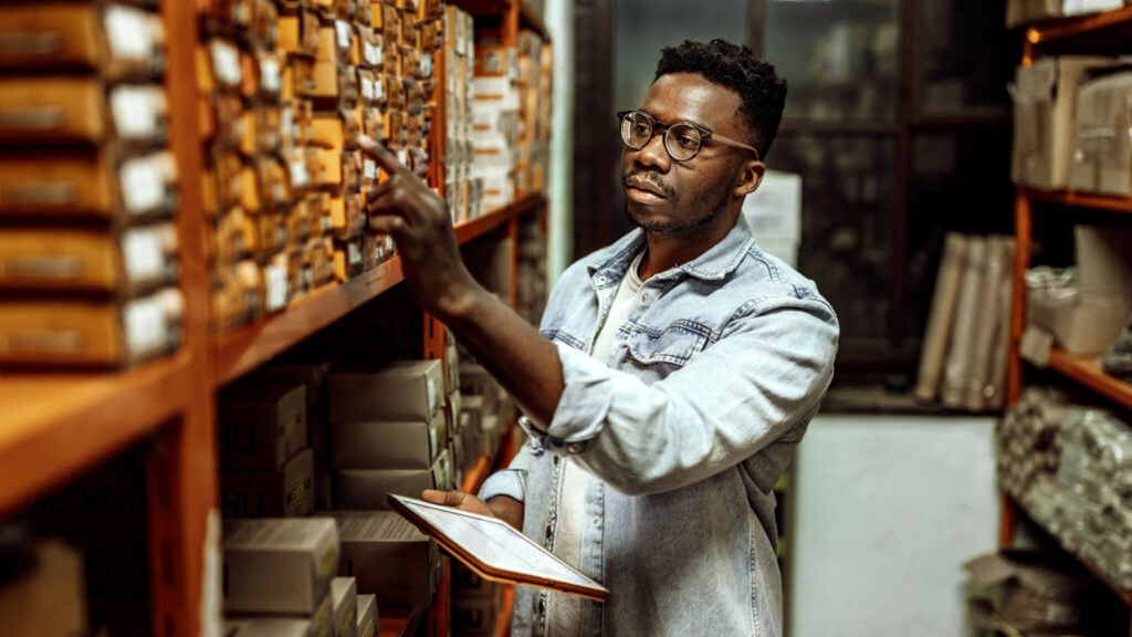 A business owner takes record of inventory in a warehouse.