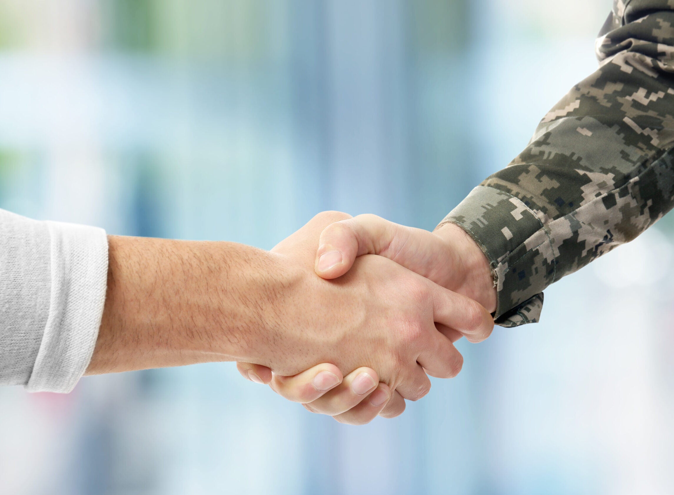 Soldier,And,Civilian,Shaking,Hands,On,Blurred,Background