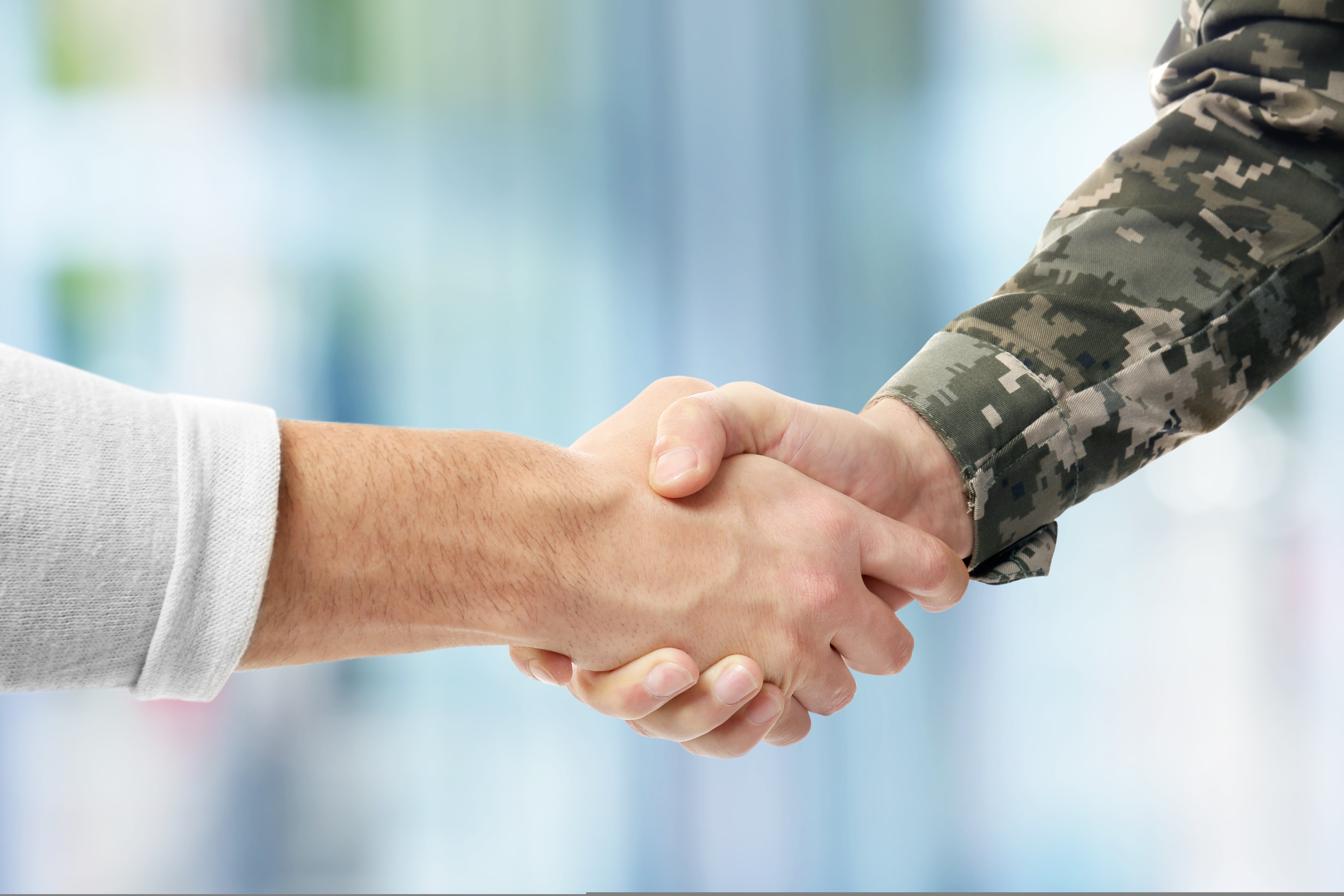 Soldier,And,Civilian,Shaking,Hands,On,Blurred,Background
