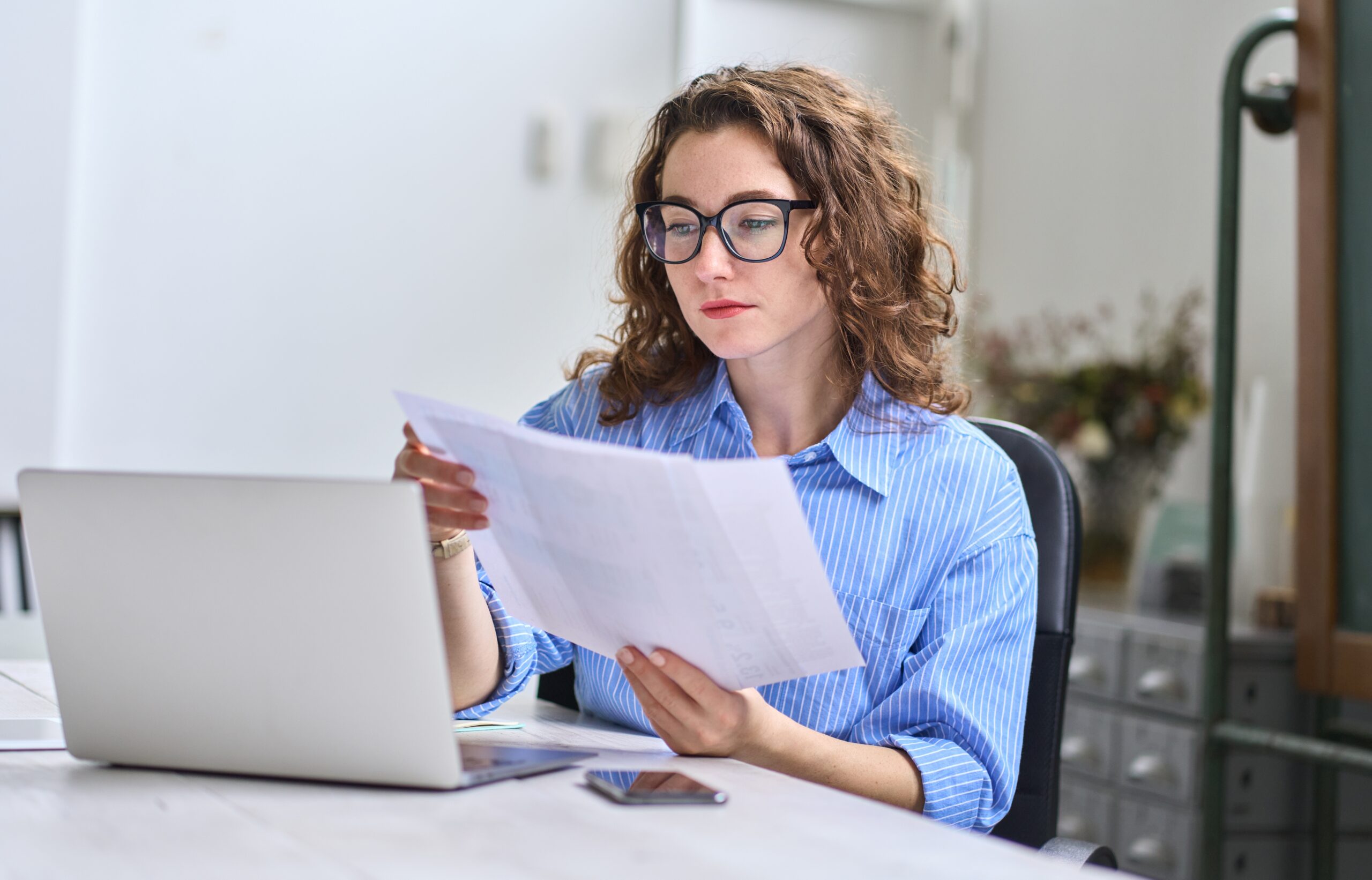 young-business-woman-at-computer-with-paperwork