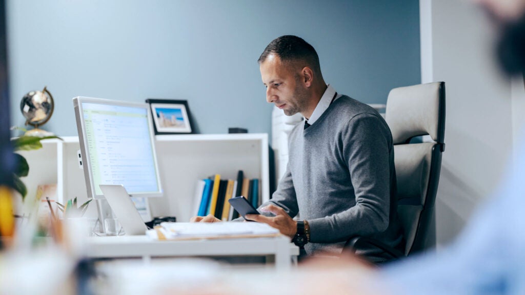 A business owner looks at his computer while reviewing financial statements.