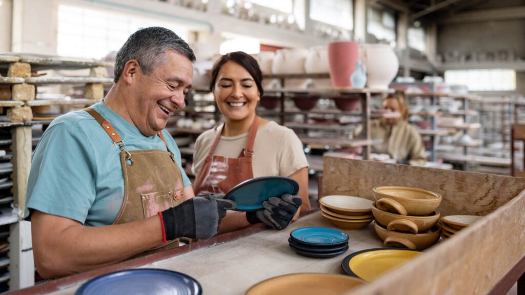 Two ceramicists admire their work after using manufacturing loans to purchase equipment.