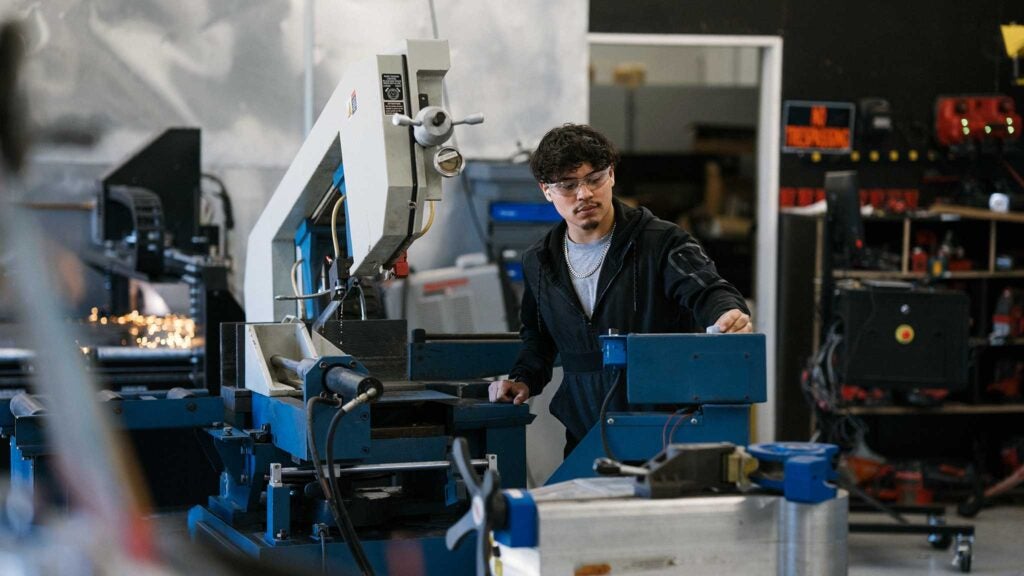 A man in uses heavy machinery that was purchased with manufacturing financing.