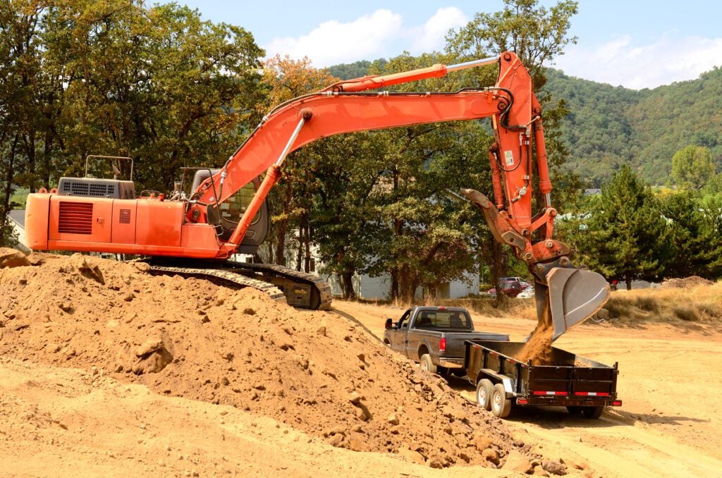 Heavy equipment machine moving dirt into a dump truck