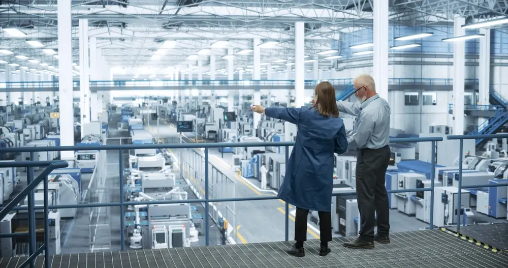 Engineers standing on a platform overlooking a manufacturing plant